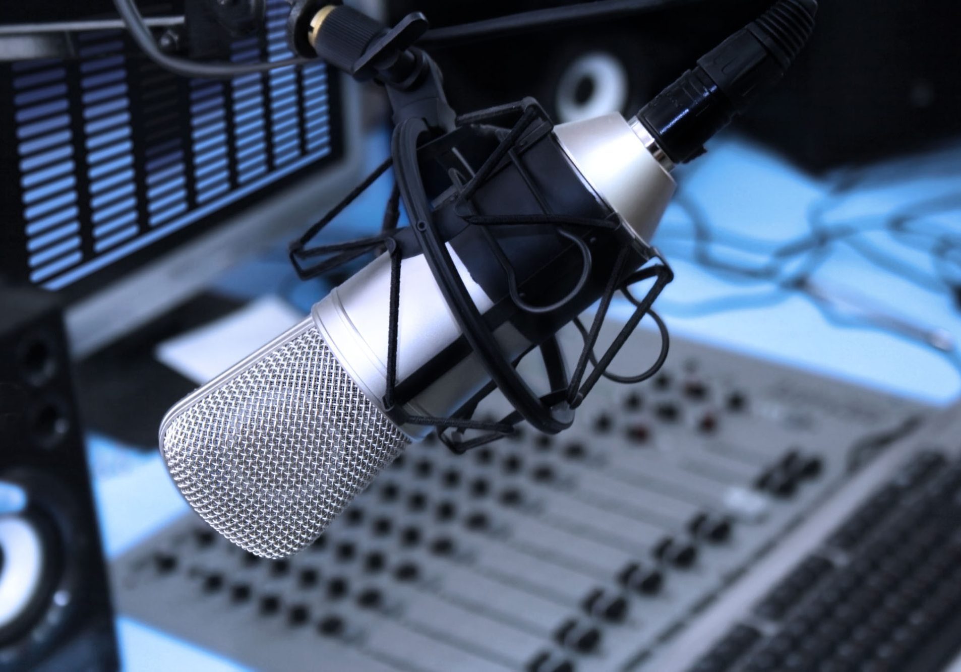 In radio studio. A mic in front of the control panel in broadcasting studio